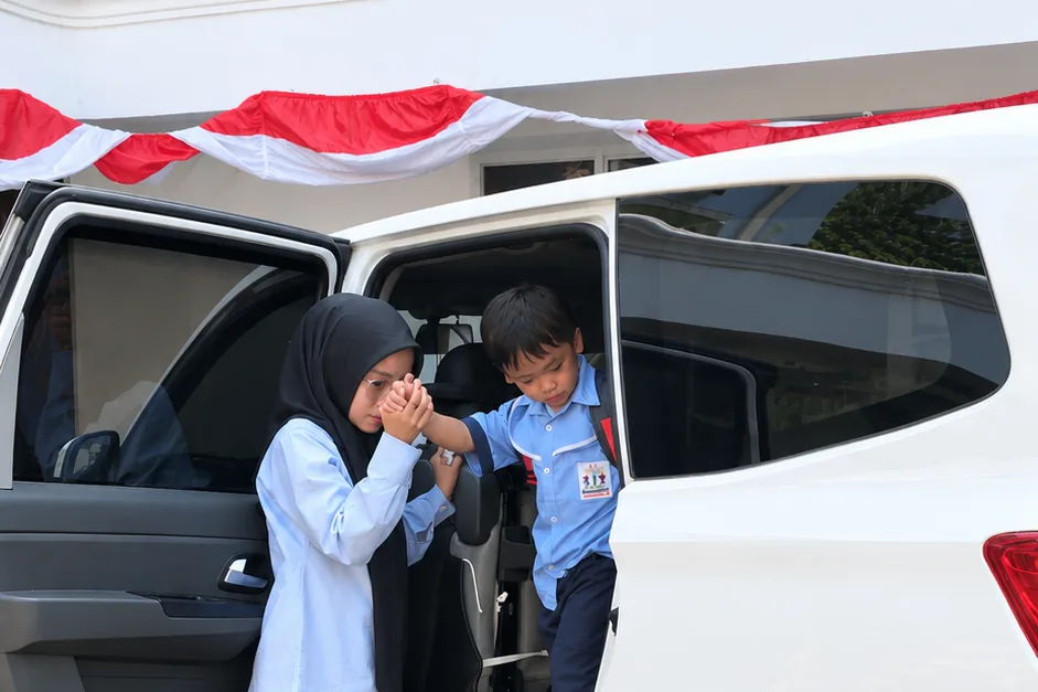 A child being helped out of the school van by a staff member